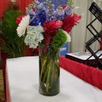 Purple, white, and red flowers in a tall glass vase