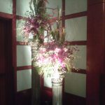 Purple flowers in a tall vase with a light shining on them